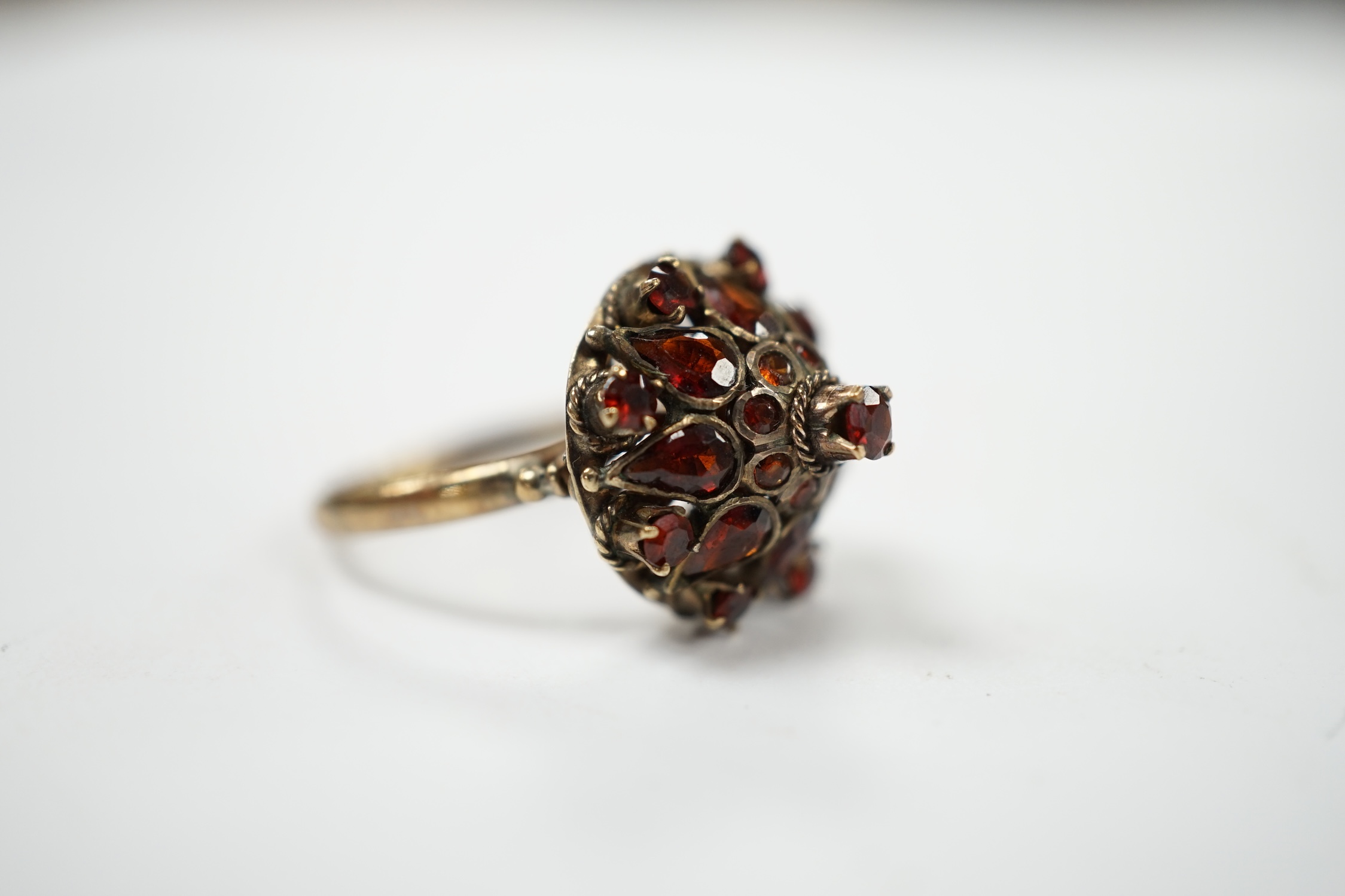A 14k and garnet cluster set domed dress ring, size M/N, gross weight 3.4 grams. Condition - fair